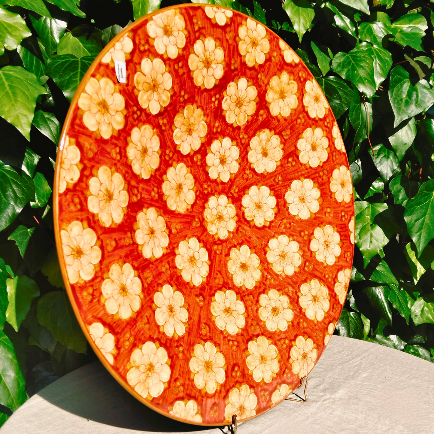 Side of the Large hand-painted Deruta ceramic decorative plate Ø 61 cm, rich red floral motif "Tappeto di Margherite", signed by artist Michela. 